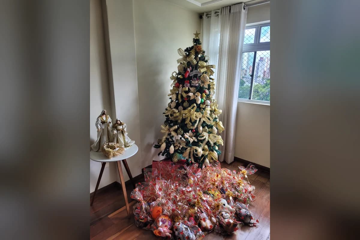 Uma árvore de Natal decorada e, embaixo dela, uma pilha de bichinhos de pelúcia embalados em plástico transparente.